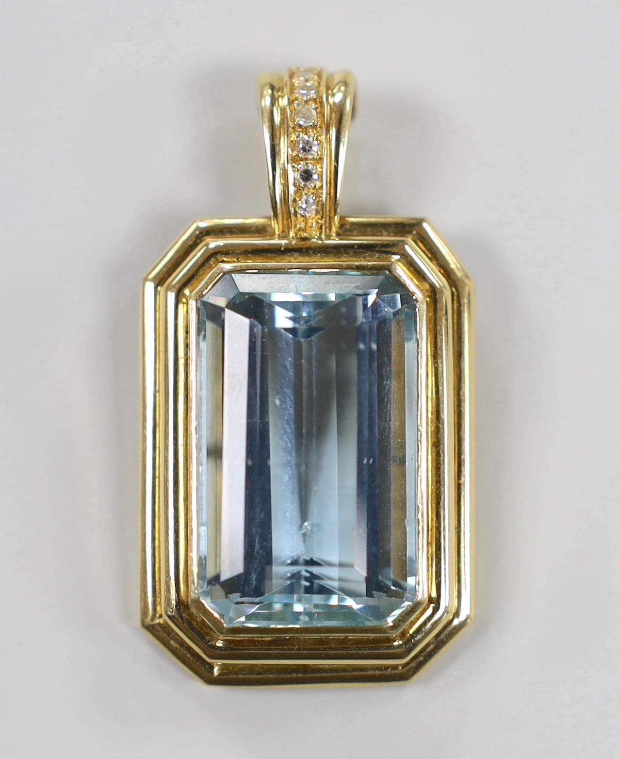 A modern 14ct gold and single stone emerald cut aquamarine set octagonal pendant, with six stone diamond chip set bale, overall 41mm, gross weight 14.6 grams.